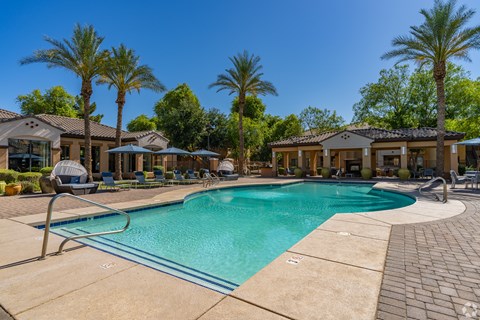 A swimming pool surrounded by palm trees and lounge chairs.