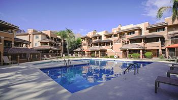 A swimming pool in front of a building with a clear blue sky.
