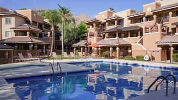 A large swimming pool in front of a building with a mountain in the background.