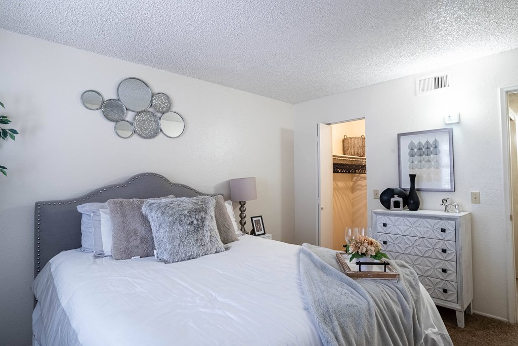 a bedroom with a large bed and a dresser with a mirror on the wall