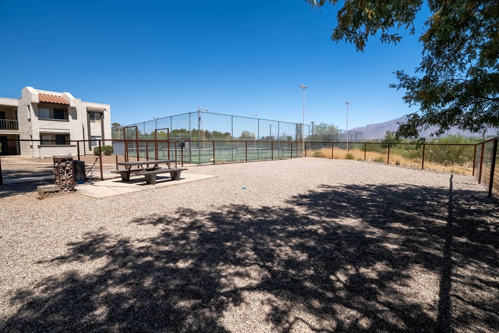 a picnic area in a park next to a tennis court and a building