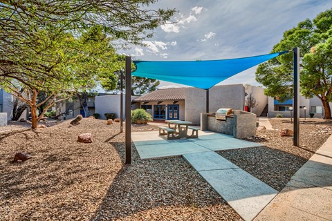 a patio with a blue canopy and a picnic table in front of a house