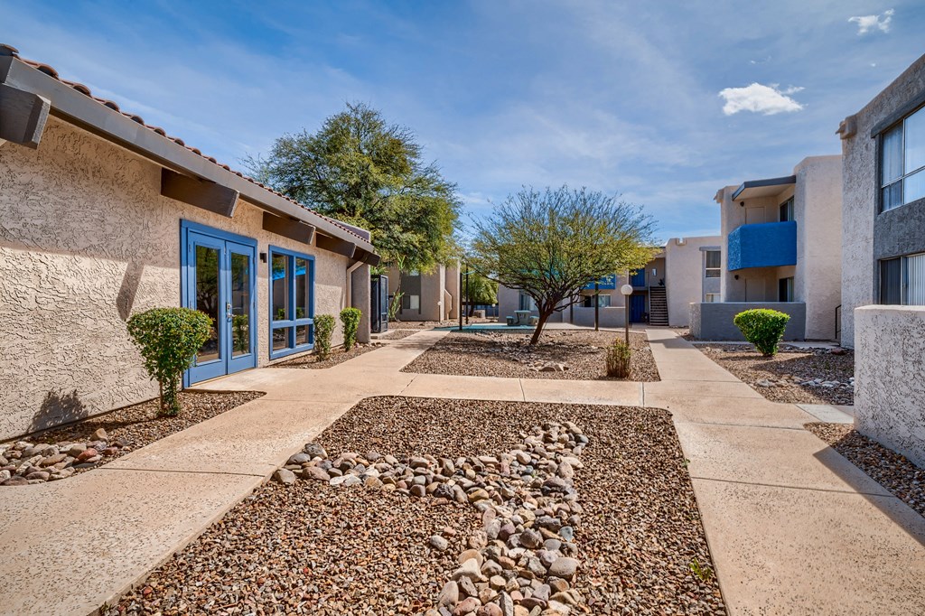 a building with blue doors and a courtyard with rocks and trees