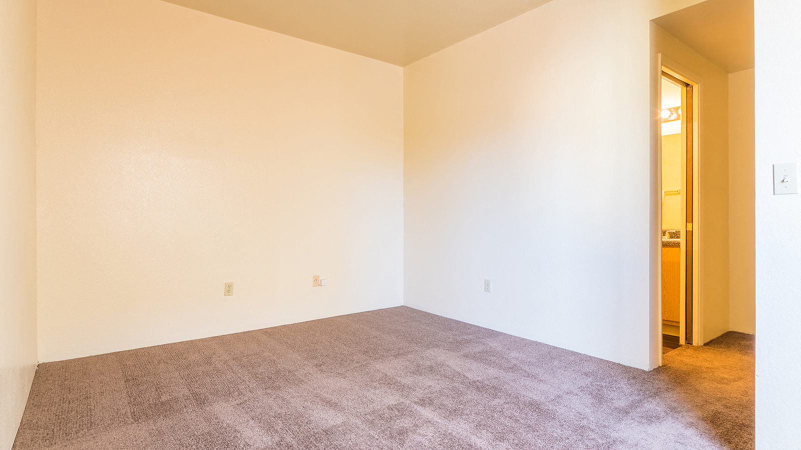 Bedroom with off white walls and brown carpet
