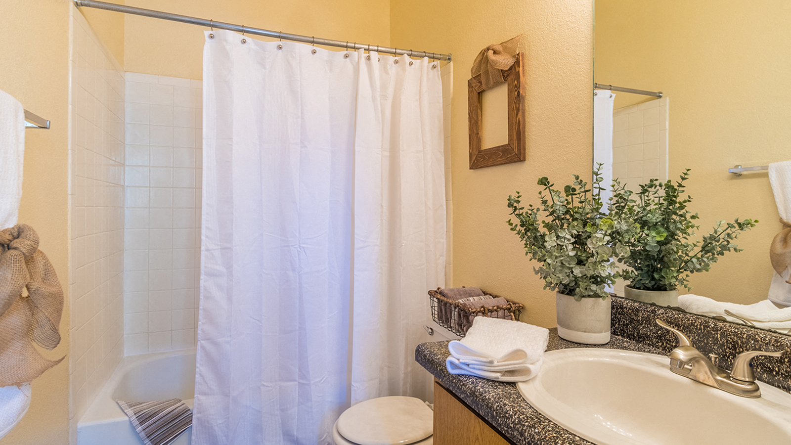 bathroom with updated sink and tub shower combo with white curtains