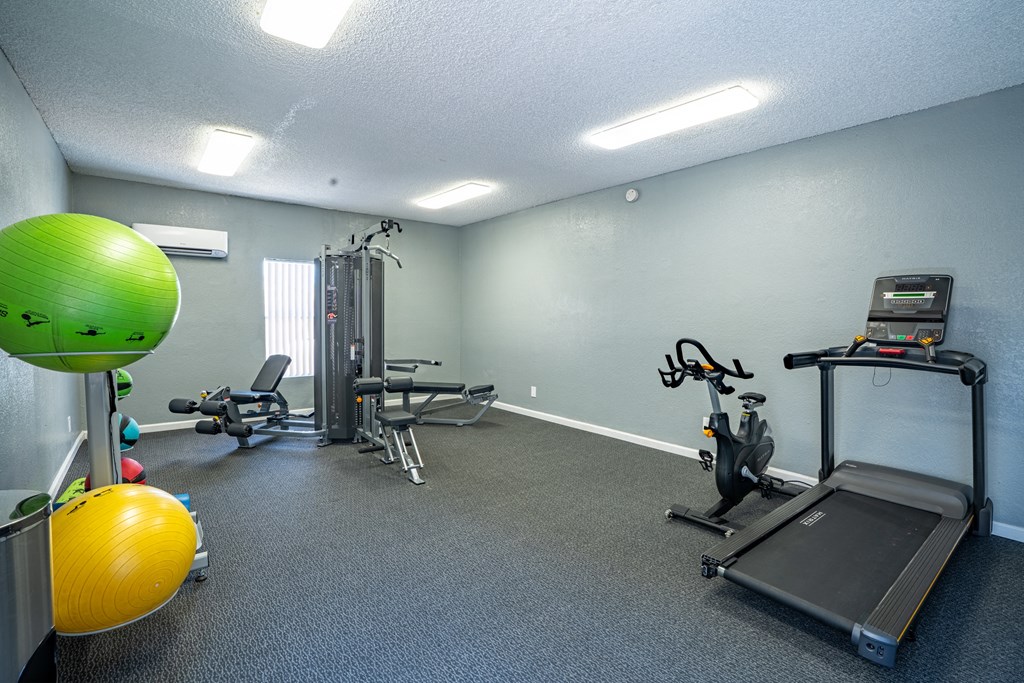 a gym with exercise equipment and a green ball in the corner