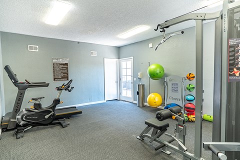 a gym with exercise equipment and a yellow ball on the wall