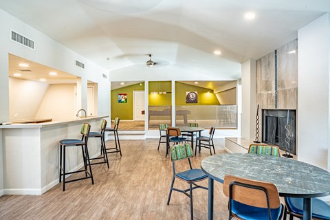 a community clubhouse with tables and chairs, bar top seating and a fireplace