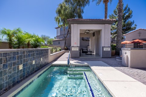 A pool with a blue tiled wall and a white building in the background.
