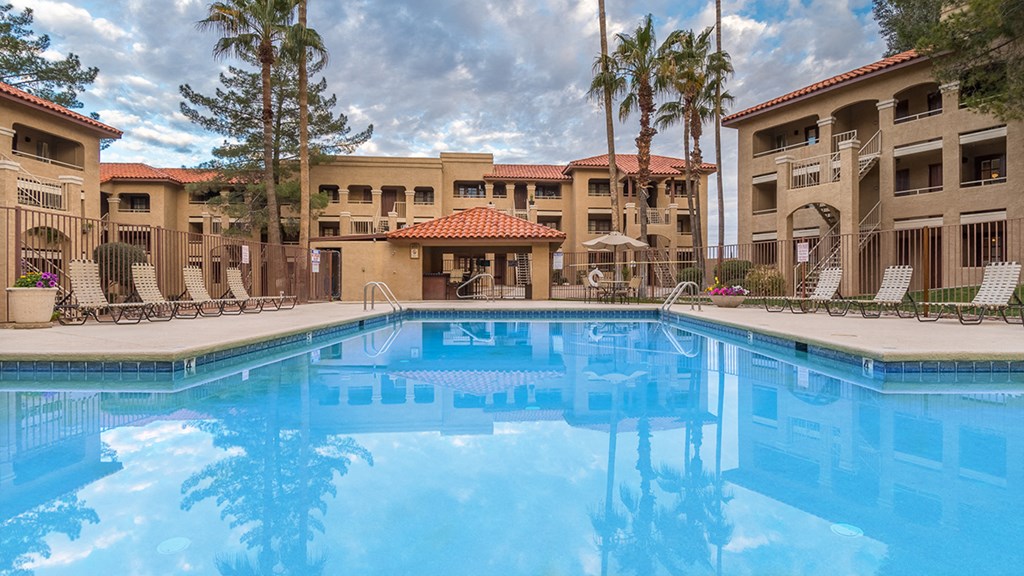 Foothills view of sparkling pool with lounging space and tall trees surrounding
