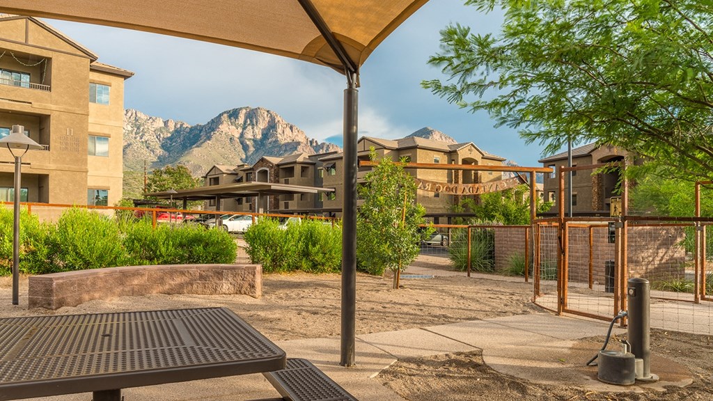 a picnic table in a courtyard with buildings and mountains in the background