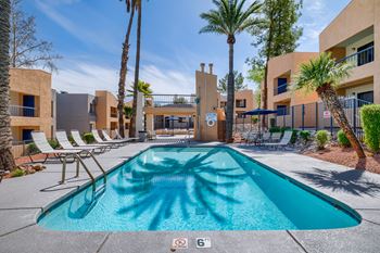 A swimming pool surrounded by palm trees and lounge chairs.