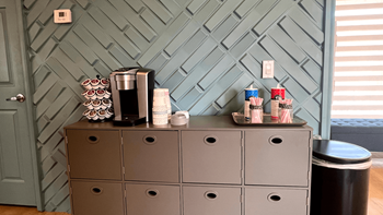 a coffee station with a gray cabinet and a blue wall with a lattice pattern