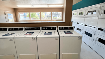 a laundry room with rows of washers and dryers