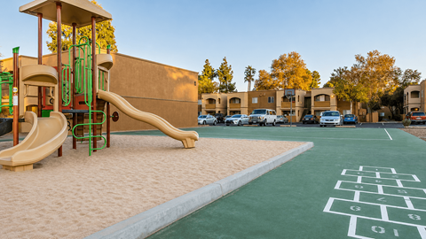 A playground with a slide and a hopscotch board painted on the ground.