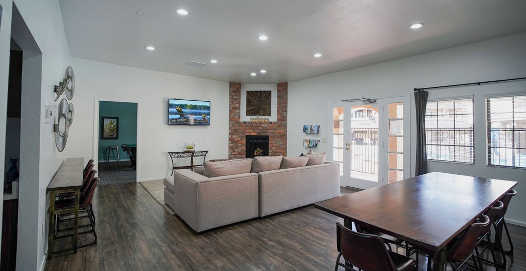 A living room with a couch, chairs, and a flat screen TV mounted on the wall.
