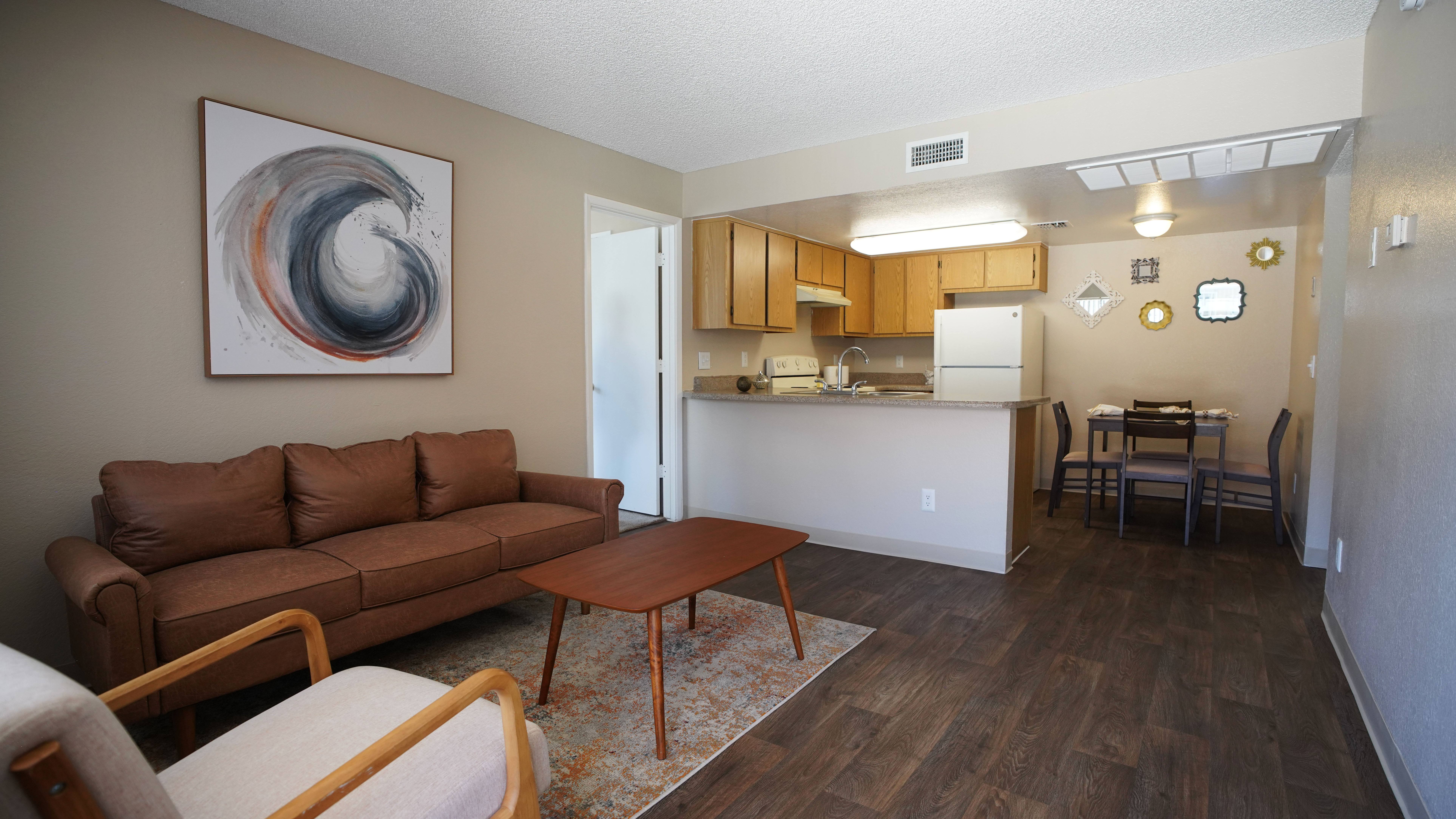 A living room with a brown couch and a painting on the wall.