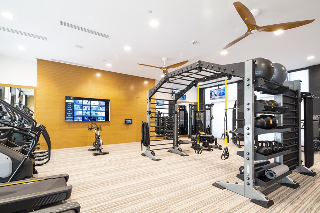a gym with weights and cardio equipment and a tv on the wall
