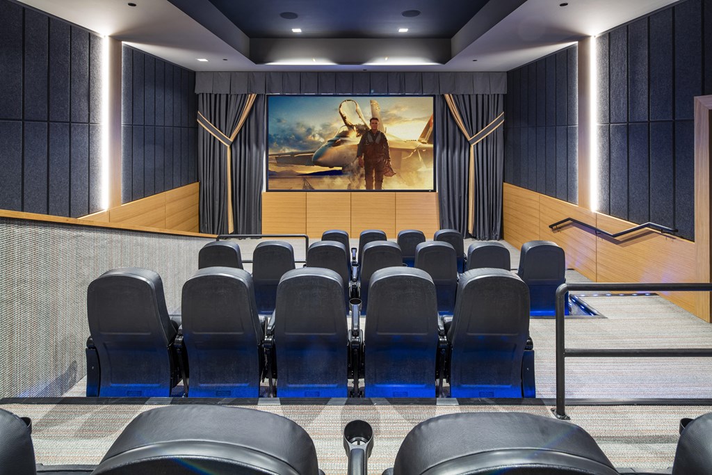 a large auditorium with blue chairs and a painting on the wall