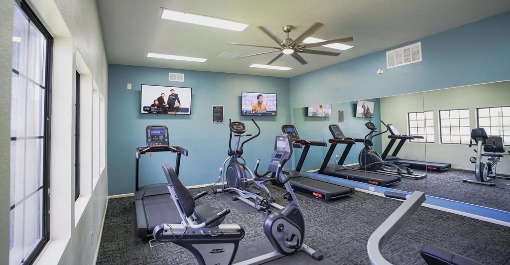 A gym with treadmills, exercise bikes, and a television.