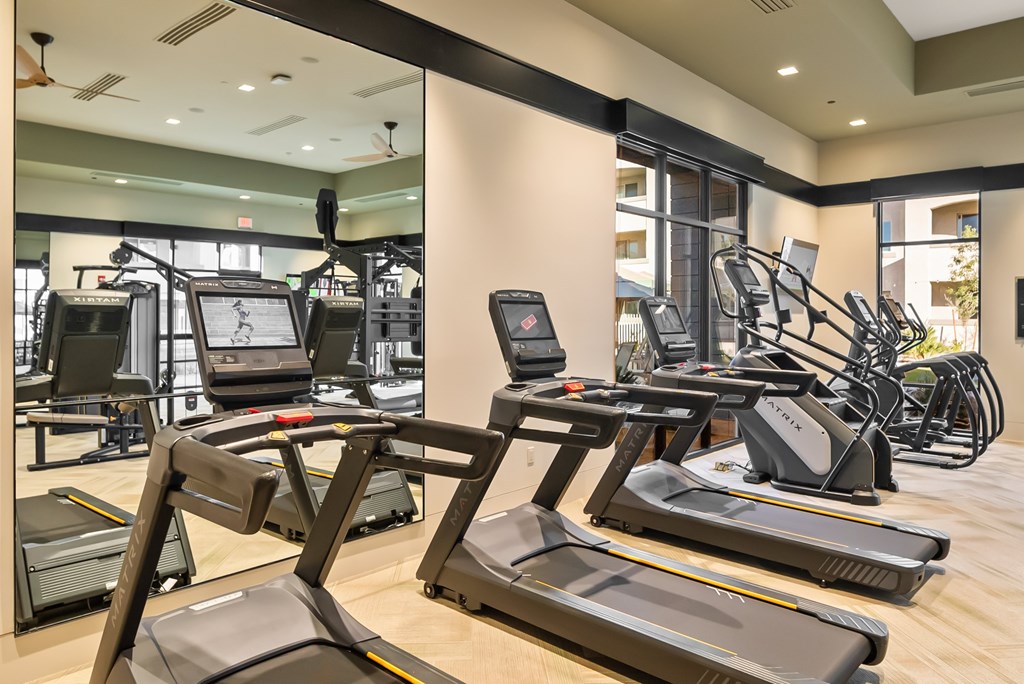 A gym with treadmills, elliptical machines, and other exercise equipment.