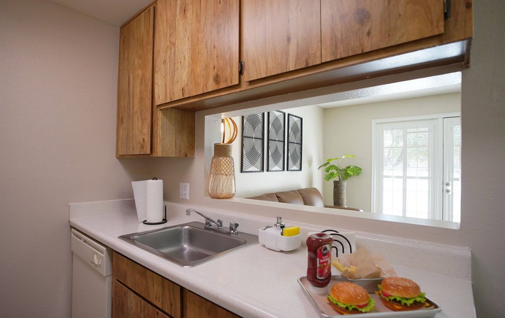 A kitchen with a white countertop and wooden cabinets.