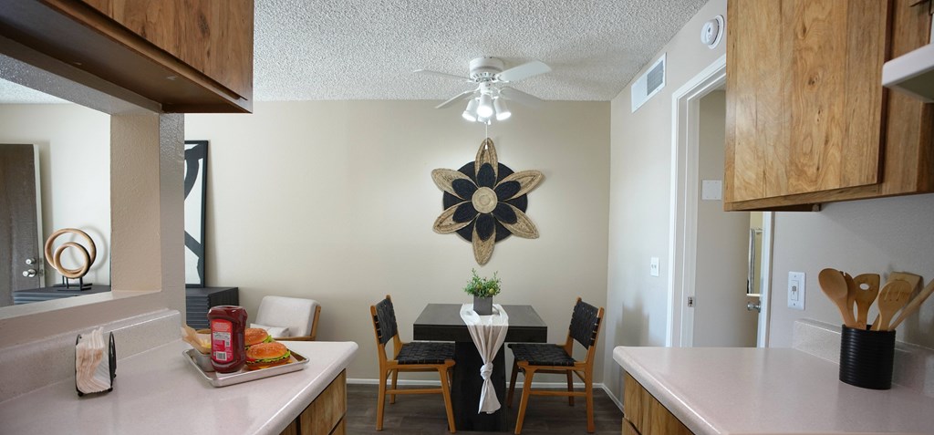 A kitchen with a table set for two and a ceiling fan.