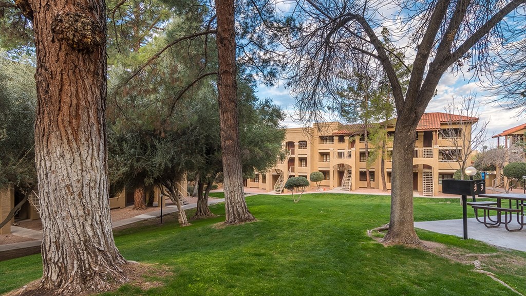A tree in a grassy area in front of a building.