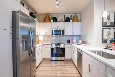 A modern kitchen with white cabinets and stainless steel appliances.