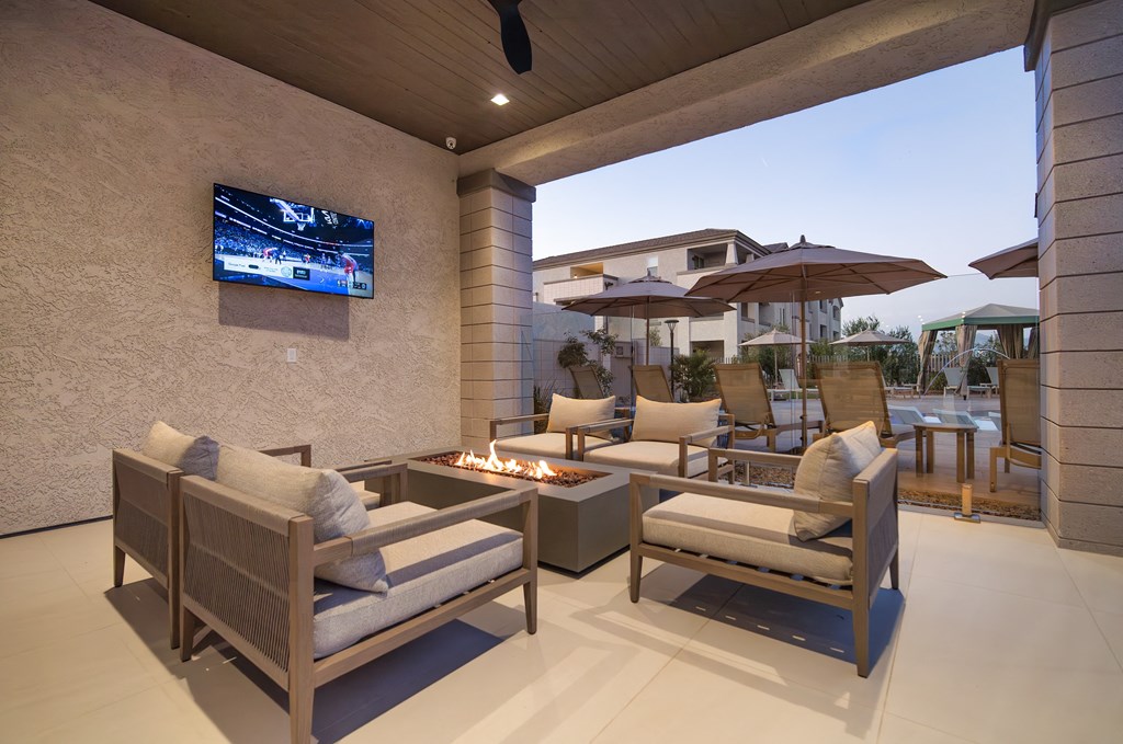 A patio with a fire pit and chairs.