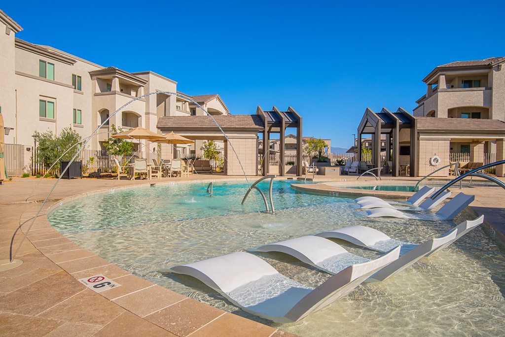 A pool with a waterfall and a white bench.
