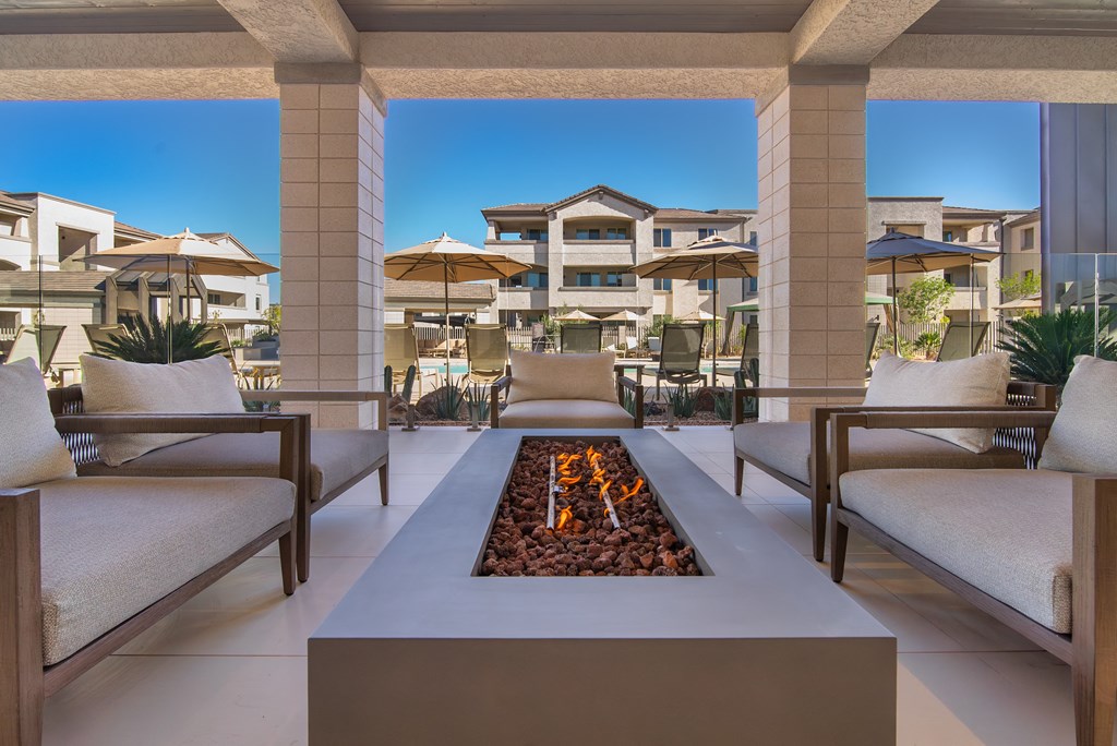 A modern outdoor seating area with a fire pit in the middle.