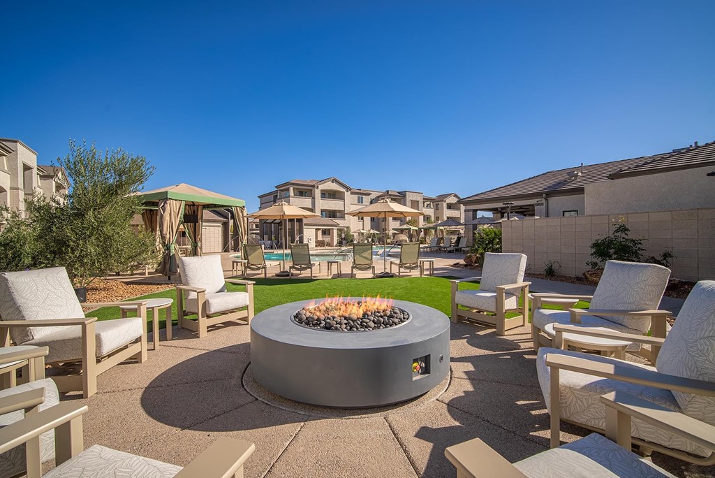A fire pit sits in the middle of a patio surrounded by chairs.