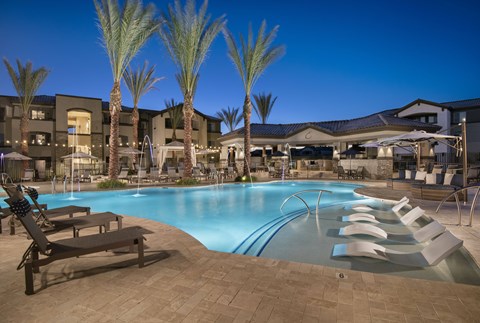 A pool surrounded by palm trees and lounge chairs.