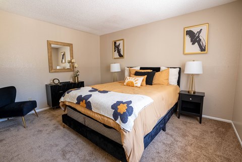 A bedroom with a bed, chair, and two lamps.