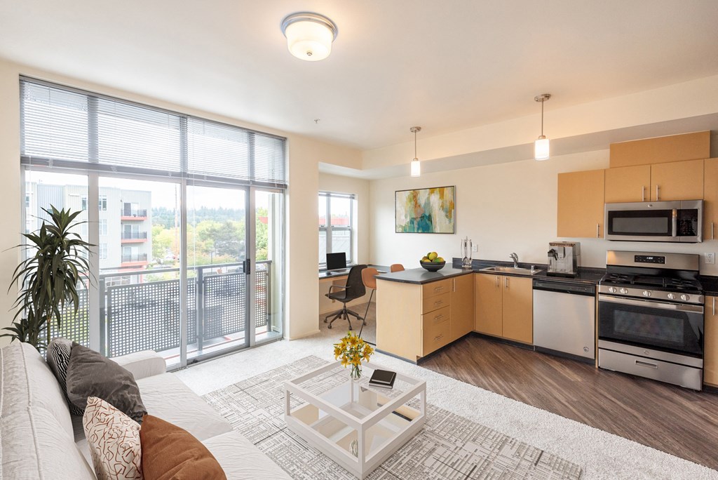 a living room with a couch and a coffee table and a kitchen with a sink