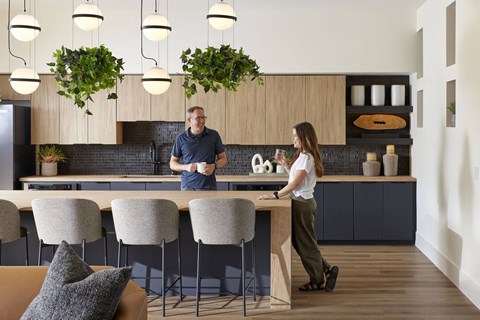 A man and a woman are standing in a kitchen with a table and chairs.