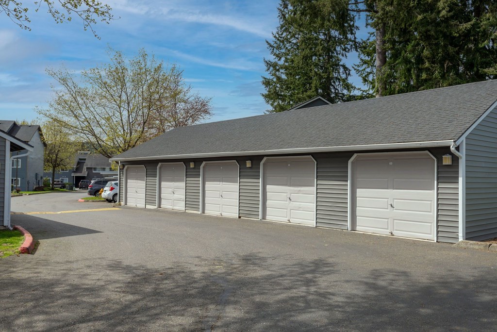 a garage with white doors on the side of a street