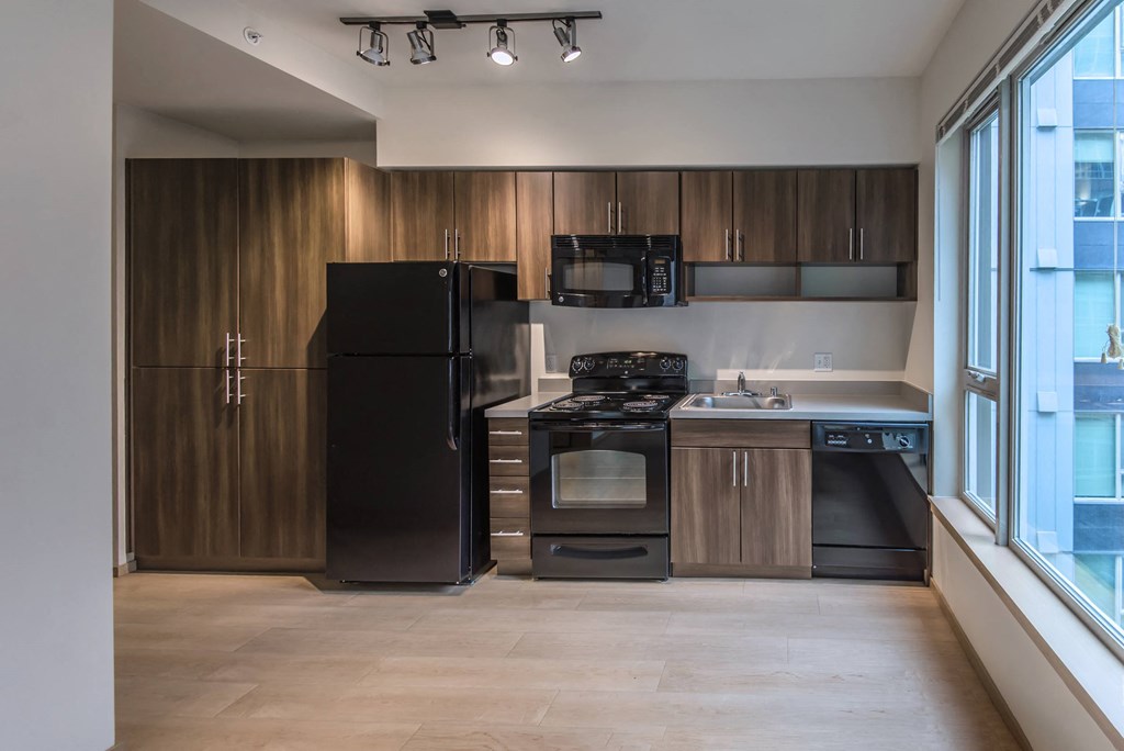 a kitchen with black appliances and wooden cabinets and a window