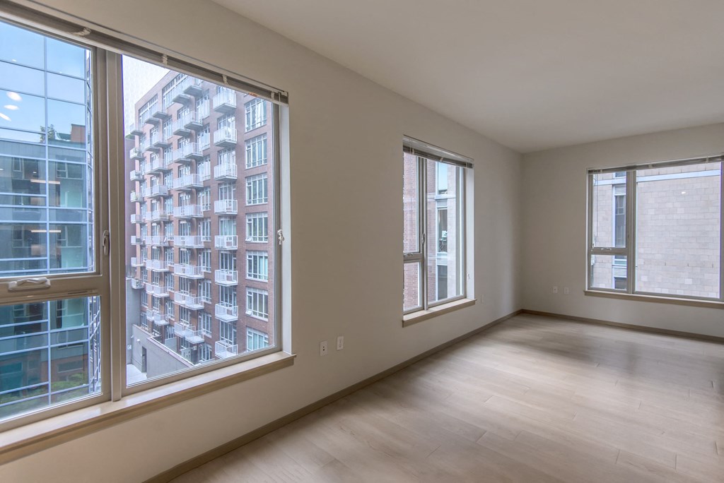 an empty living room with large windows and wood floors