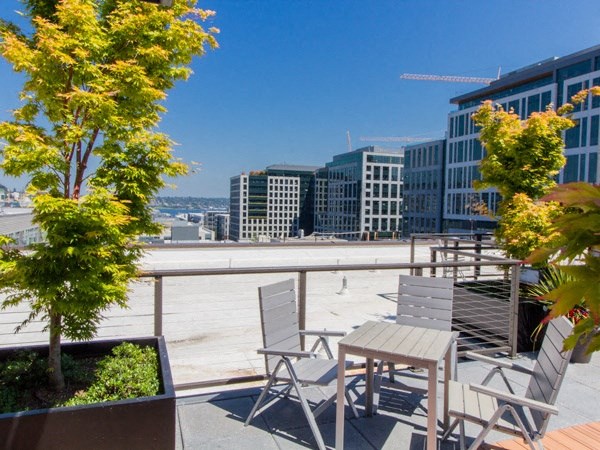 a roof deck with tables and chairs and a view of the city