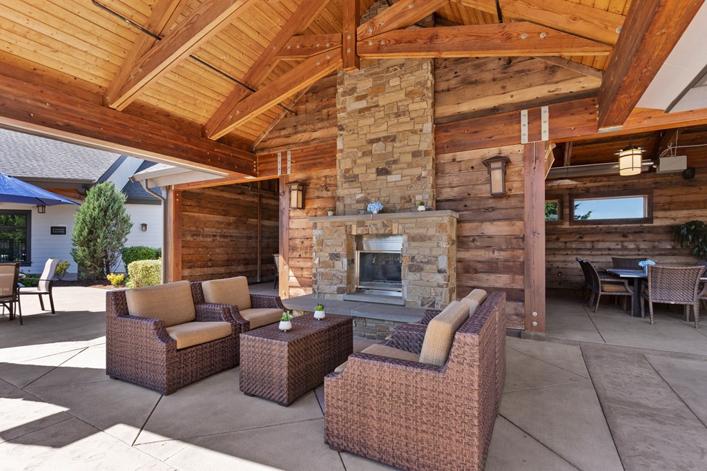 a covered patio with furniture and a stone fireplace