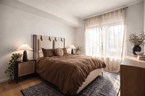 A bedroom with a large bed and a window with curtains.
