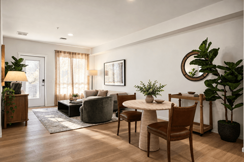 A living room with a grey couch, a white table, and brown chairs.