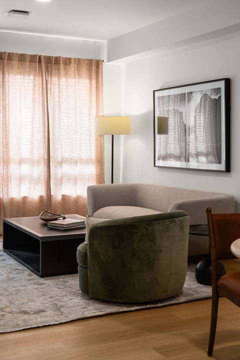 A living room with a green armchair, a black side table, and a framed picture on the wall.