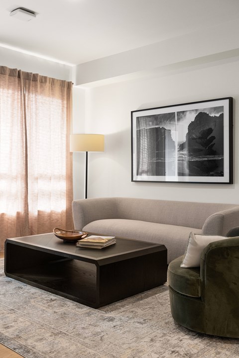 A living room with a green armchair, a coffee table, a lamp, and a framed picture on the wall.