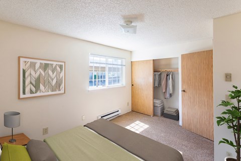 A bedroom with a bed, a lamp, a painting, and a closet.