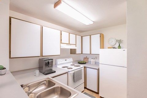 A kitchen with white appliances and a stainless steel sink.