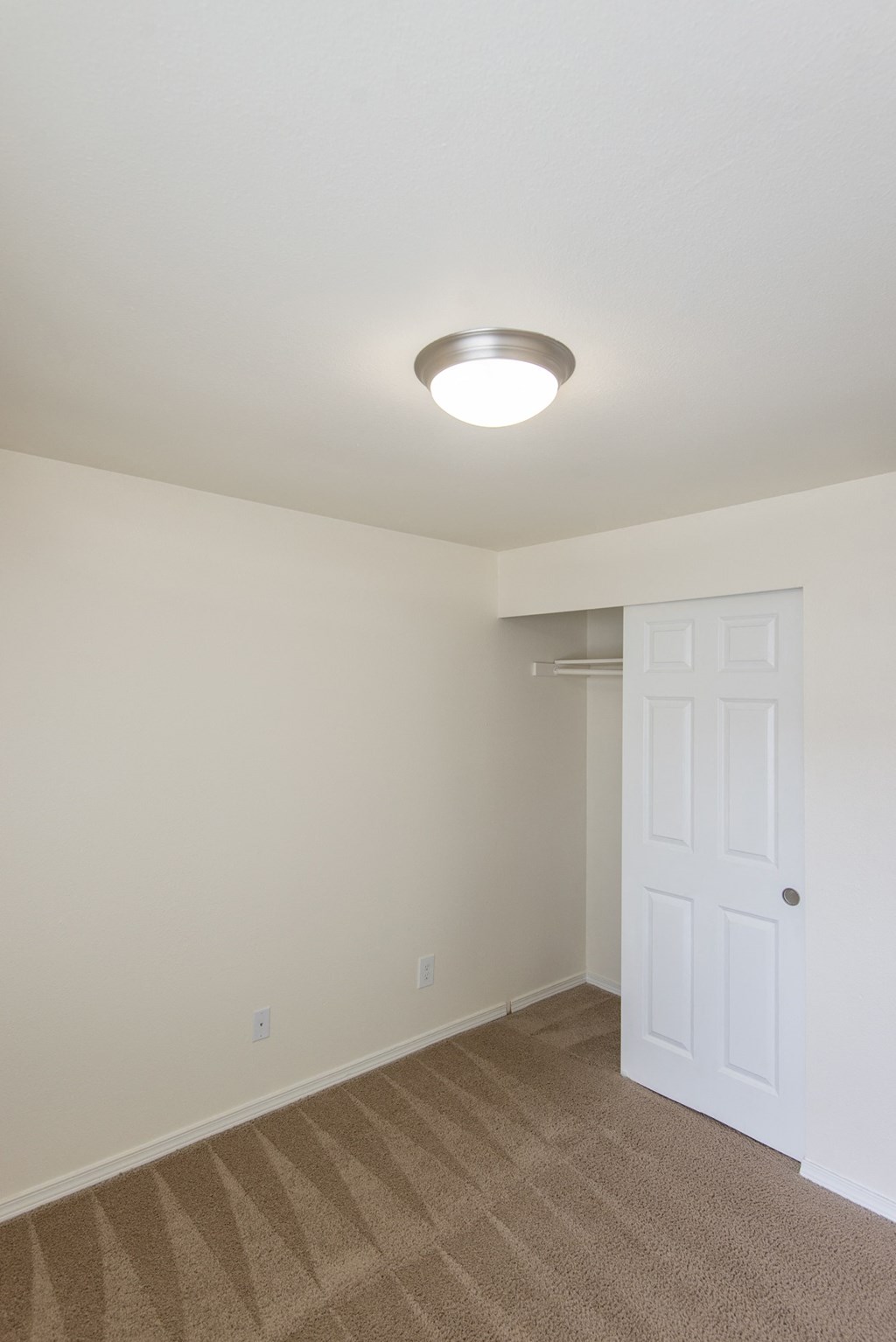 an empty bedroom with a closet and a white door