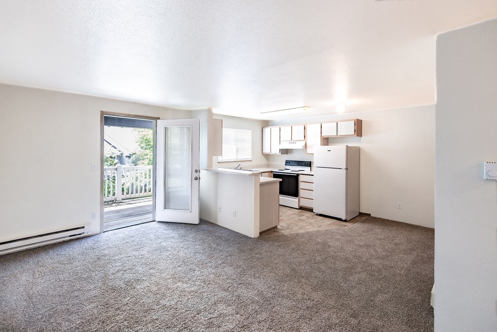 an open living room and kitchen with a sliding glass door to a balcony